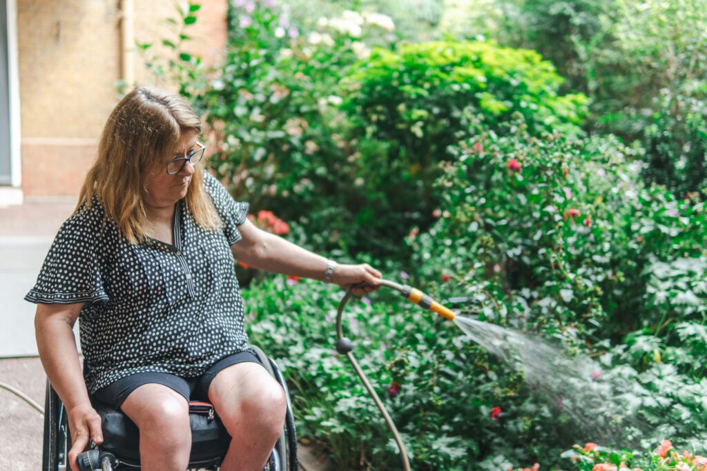 A woman watering plants in her garden with support in Lilydale