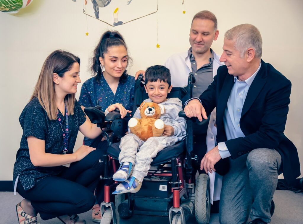 A family and support workers gathered around a young boy who uses a wheelchair