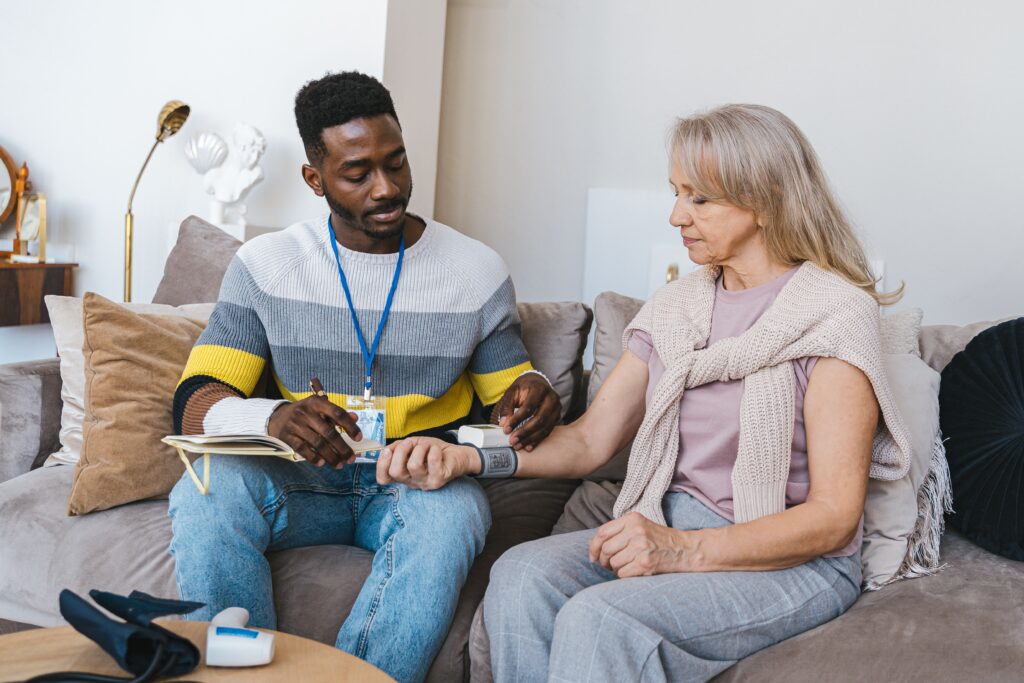 A support worker sitting with a woman on her couch at home