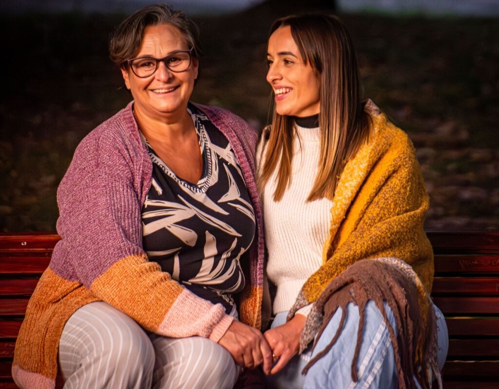 Two women sitting together and smiling outdoors in Glen Waverley