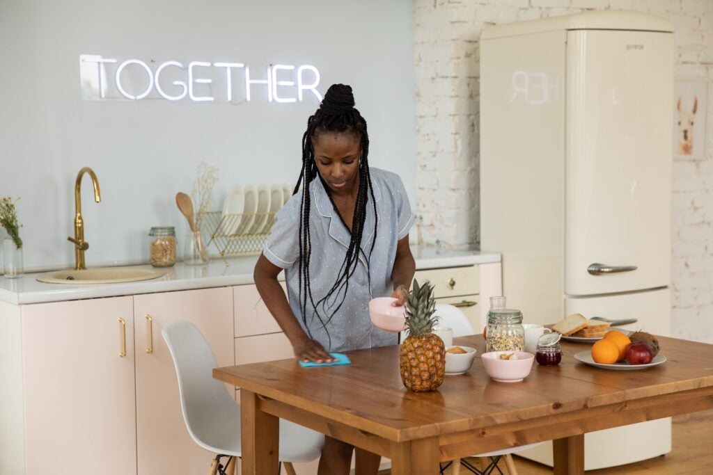 A support worker cleaning and tidying a kitchen bench in a client’s home