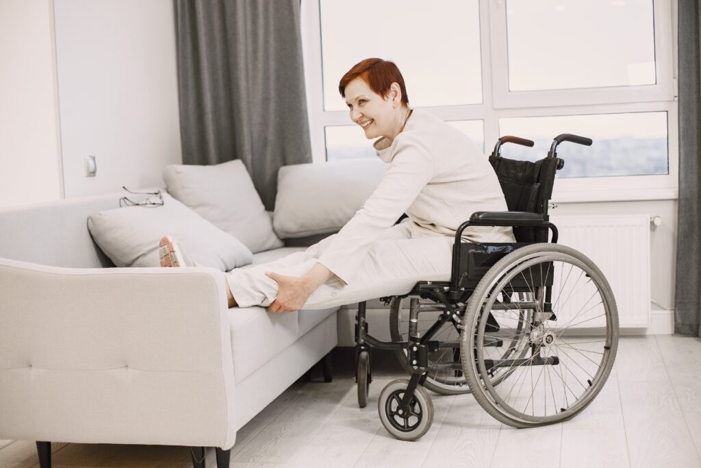 A support worker helping a woman move safely from her wheelchair to the sofa