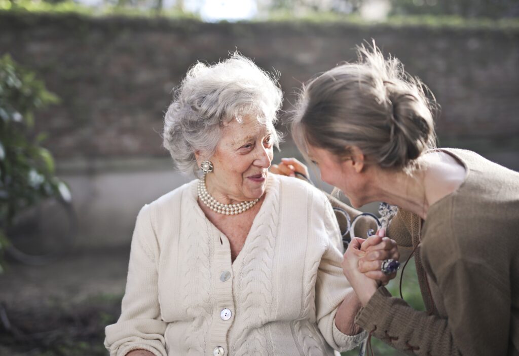 An older woman smiling closely with her carer during a respite visit at home