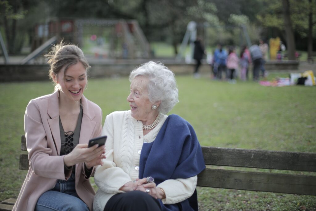 A support worker and an older woman chatting together on a park bench in Ringwood