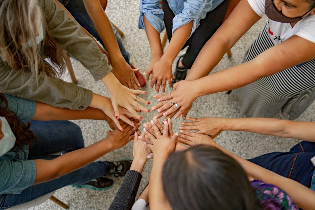 A group of people placing their hands together in a circle, representing teamwork